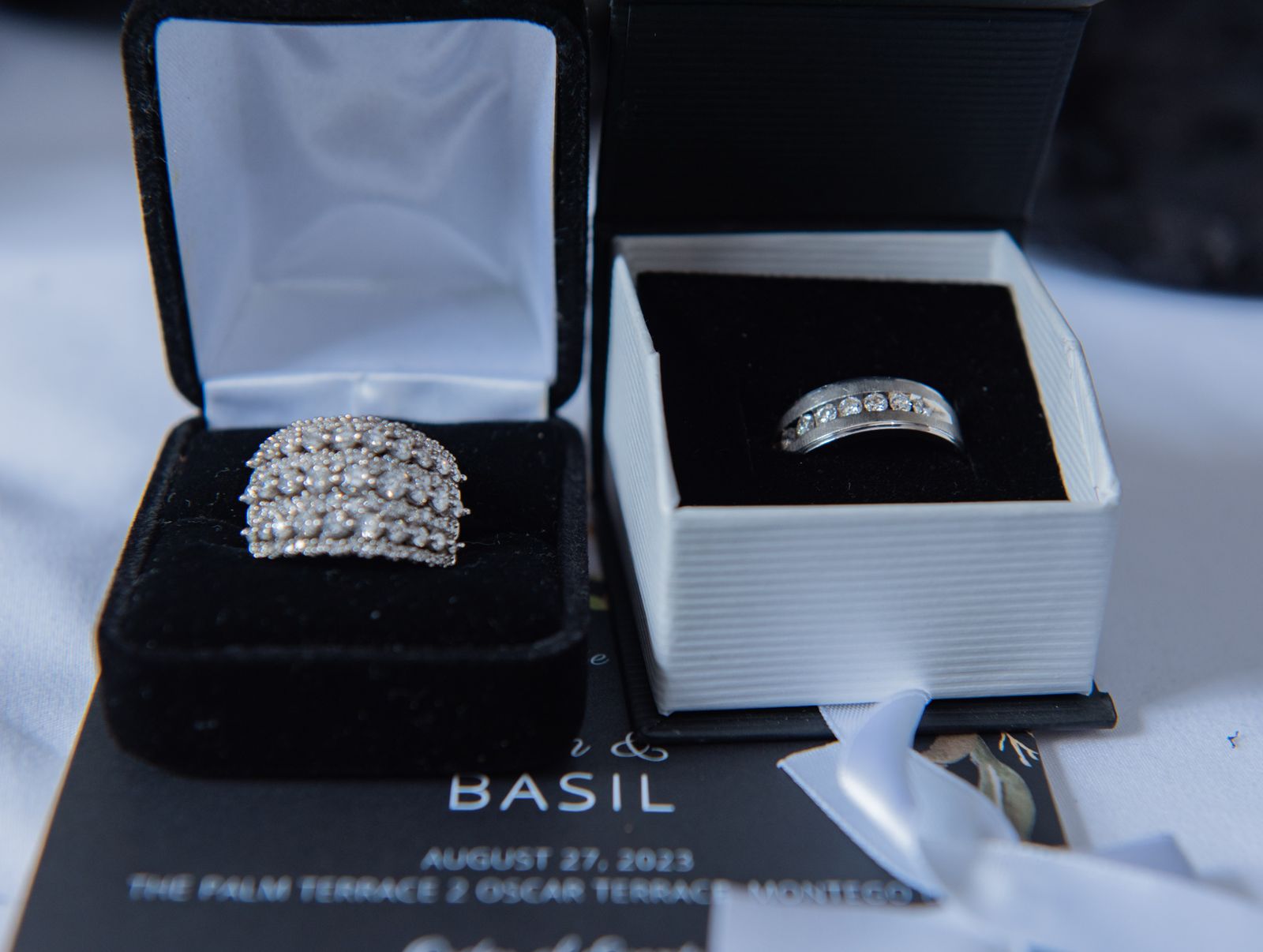 Two wedding rings in open boxes on a dark surface