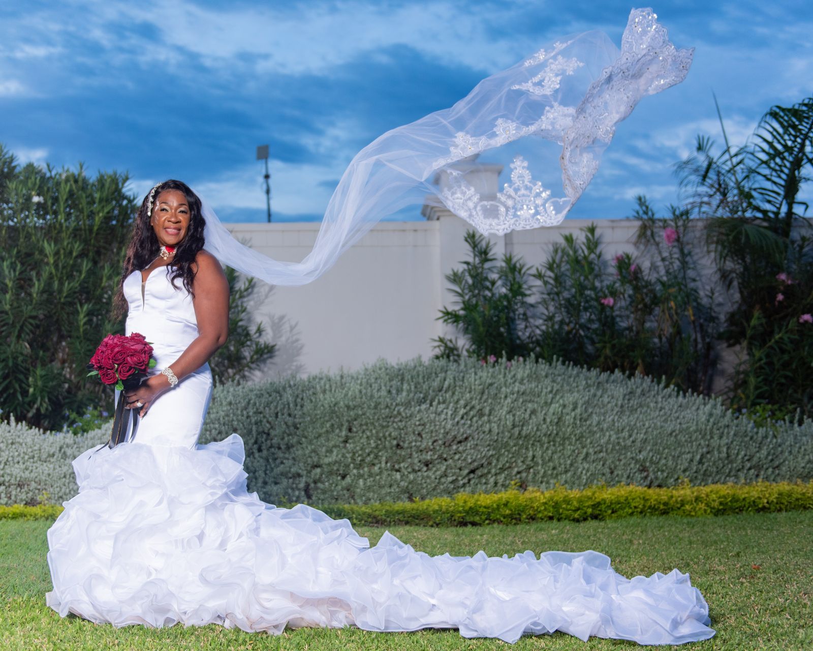 The veil caught mid-air above the bride as she looks down at her bouquet
