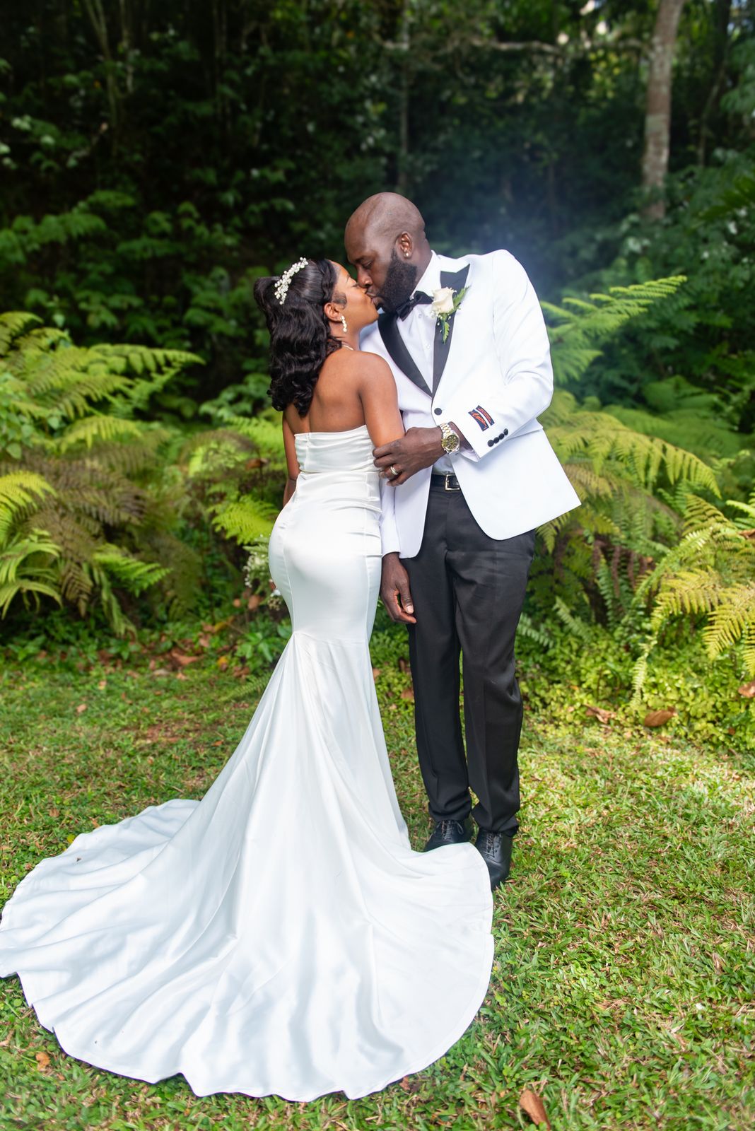 The couple kissing in front of dense green ferns