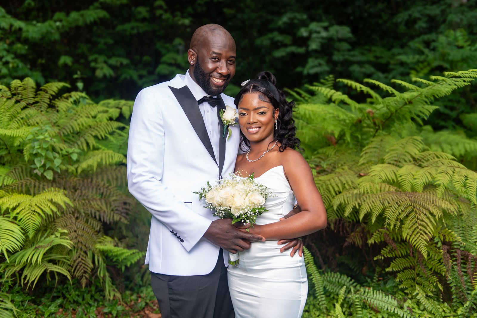 The couple standing together among tree ferns, the bride looking up at him
