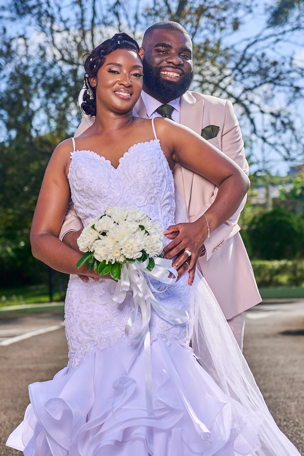 The bride and groom together on the driveway, her ruffled gown filling the frame